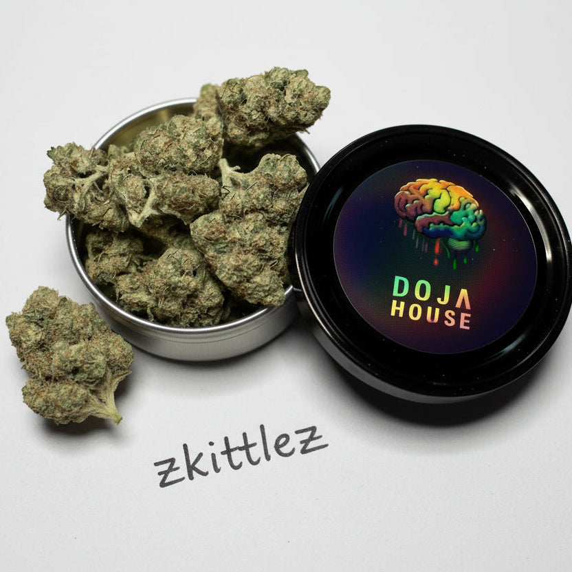 Bowl of cannabis buds next to a container with 'Doja House' branding on a marble surface.