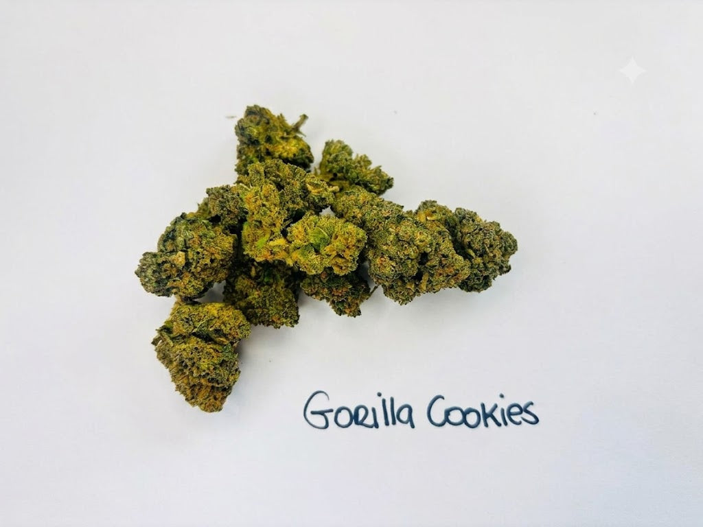 A small cluster of dried green and yellowish-brown buds on a plain white background, with the handwritten text 'Gorilla Cookies' written vertically to the left.